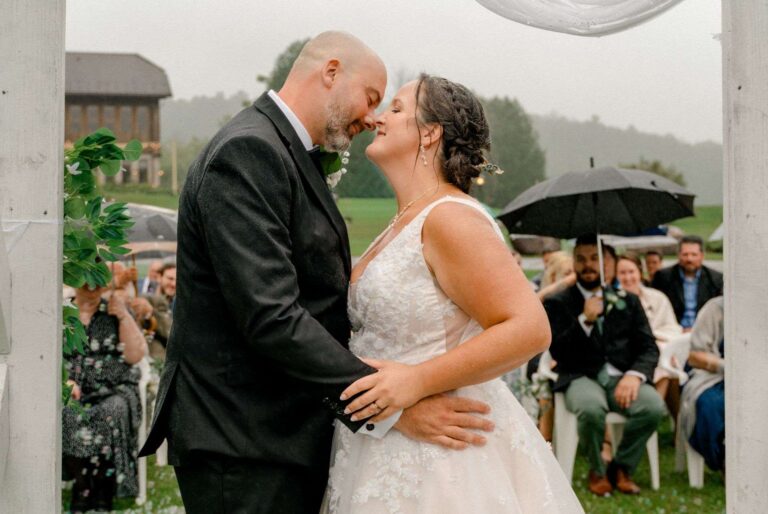Couple qui s'embrasse pendant leur mariage, entouré de leurs invités