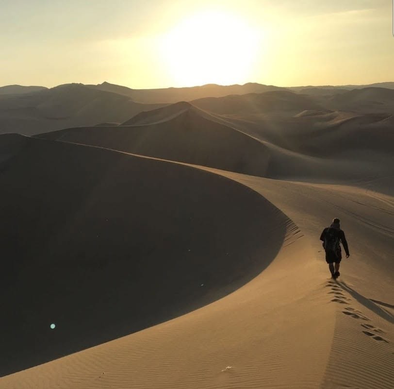 Simon Patrie marchant seul dans les dunes du désert de Huacachina au Pérou — le voyage déclencheur de sa passion pour la photographie