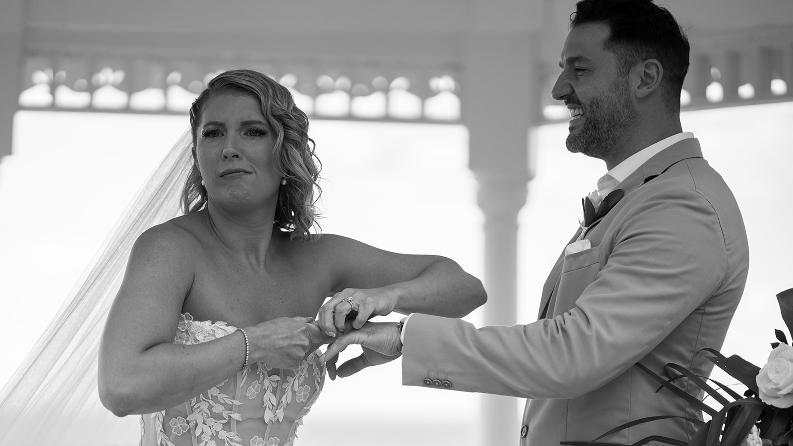 Mariée qui force pour passer l'alliance au doigt enflé du marié, qui éclate de rire, lors d'un mariage en Jamaïque