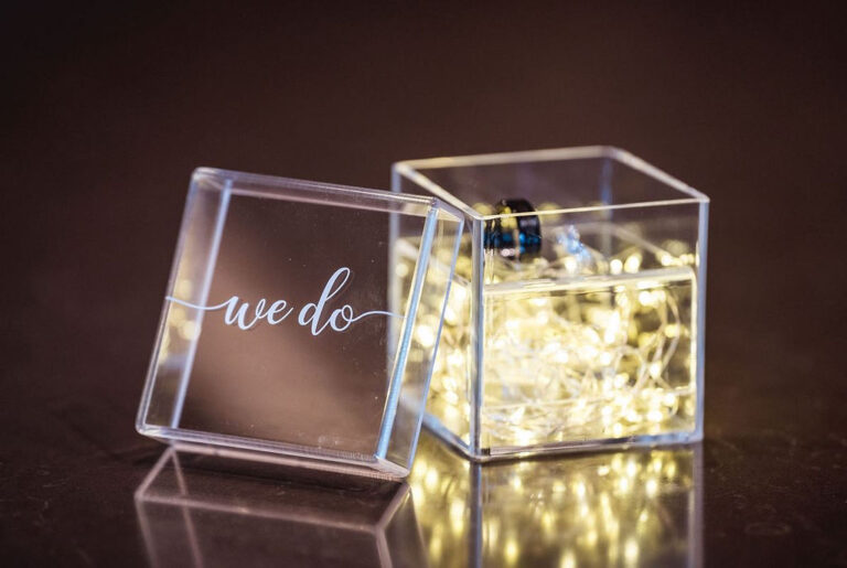 Alliances de mariage dans une boîte acrylique « we do » illuminée par une guirlande lumineuse dorée