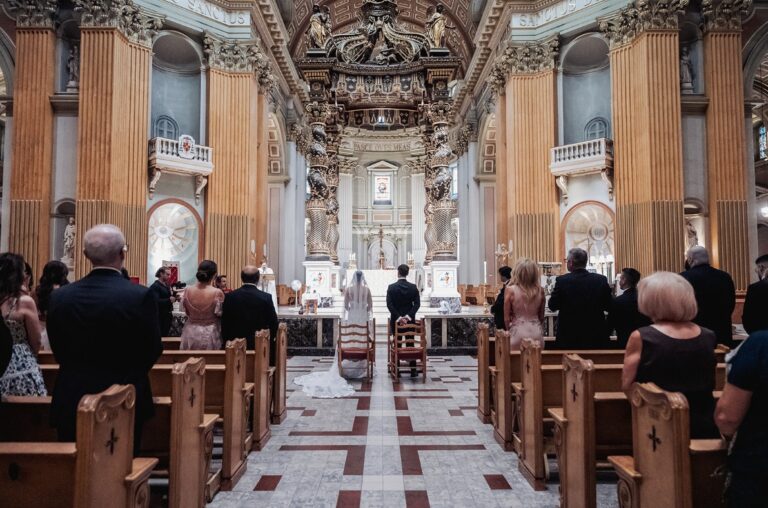 Cérémonie de mariage à l’église : les mariés assis devant l’autel doré, invités debout dans les bancs