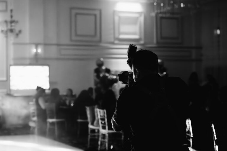 Photographe de mariage au travail, en silhouette, dans une salle de réception en soirée